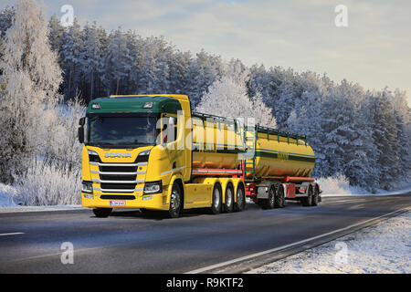 Bunte Tankwagen der Kuljetusliike K Pekki Antriebe durch eine Milchglasscheibe Winterlandschaft in der Dämmerung auf den Weg, um die Last in Salo, Finnland, 2018. Stockfoto