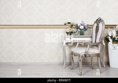 Ein Fragment eines retro Interieur mit einem Sessel und einen Schreibtisch, auf dem ein Telefon und eine Vase mit Blumen befindet. Stockfoto