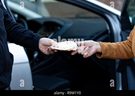 Ein Mann zahlt das Auto zu einer alten Dame, nachdem Sie es gekauft haben. Stockfoto