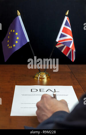 Brexit Konzept. Männliche Hand von hinten Unterzeichnung Blatt Papier 'Deal' auf einem Tisch mit Tischplatte UK und EU-Flaggen unter der Leitung hinter Stockfoto