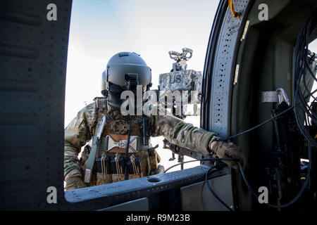 Die US-Armee Flight Engineer in der 738Th Air Expeditionary Beratenden Gruppe in einem afghanischen Luftwaffe UH-60 Blackhawk Dez. 5, 2018, während in den teilnehmenden NATO-led der entschlossenen Unterstützung der Mission in Afghanistan. Die Mission von Zug, beraten, unterstützen, Command-Air ist zu Trainieren, beraten, und die afghanischen Partner unterstützen eine Professionelle, leistungsfähige und nachhaltige Air Force zu entwickeln. TAAC-Air nutzt Zug, beraten und unterstützen Aktivitäten im Konzert mit starken persönlichen Beziehungen zu professionellen afghanischen Flieger in der Lage, Planung zu erstellen, zu führen, zu beschäftigen, und Aufrechterhaltung entscheidender Airpower. (U.s. Stockfoto