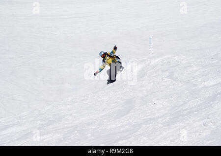 Snowboarder auf verschneiten Skipiste bei hohen Winter Berge im sonnigen Tag springen Stockfoto