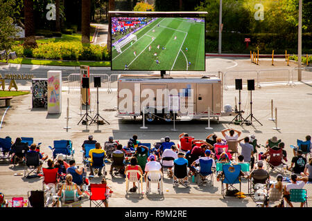 Tagsüber ein Publikum Uhren eine Fußball-WM Spiel auf einen gigantischen Outdoor TV-Bildschirm in Costa Mesa, CA. Stockfoto