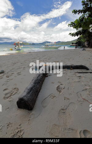 Zwei Palm Tree trunks auf dem Sand des Cudugnon Cave Strand bildet einen 90 Grad Winkel auf die SE gegenüber Lagen-Dibuluan Inseln und Palawan ma Stockfoto