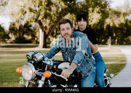 Portrait von attraktiven gut aussehende junge moderne Trendy modische Kerl Mädchen Paar Reiten auf Grün Motorrad Cruiser Classic Bike in der Liebe Stockfoto