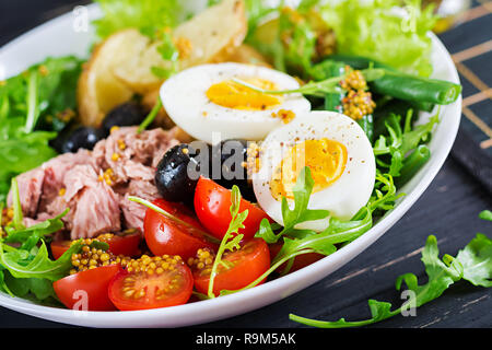 Gesunde herzhaften Salat mit Thunfisch, grüne Bohnen, Tomaten, Eier, Kartoffeln, schwarze Oliven close-up in einer Schüssel auf den Tisch. Salat Nicoise. Französische Küche. Stockfoto