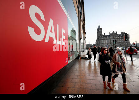 Käufer übergeben einen Verkauf Zeichen im Fenster von H&M an der Princes Street, Edinburgh, während der Boxing Day Vertrieb. Stockfoto