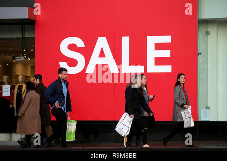 Käufer übergeben einen Verkauf Zeichen im Fenster eines Store auf der Princes Street, Edinburgh, während der Boxing Day Vertrieb. Stockfoto