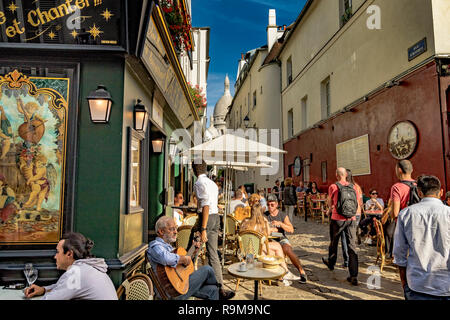 Ein Mann sitzt das Spielen einer Gitarre außerhalb de La Bonne Franquette, Café, Restaurant, während Menschen Mittagessen in der Sonne, genießen Sie Montmartre, Paris Stockfoto