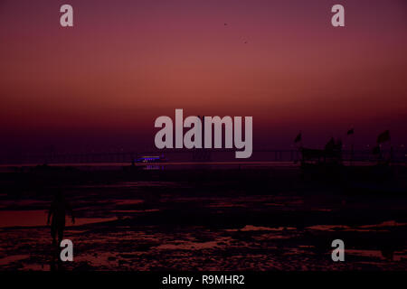 Mumbai, Indien. 25. Dezember, 2018. Ein Mann gesehen, der im Strand bei Sonnenuntergang im Hintergrund der Bandra-Worli Sea Link Brücke in Mumbai. Azhar Khan/Alamy leben Nachrichten Stockfoto