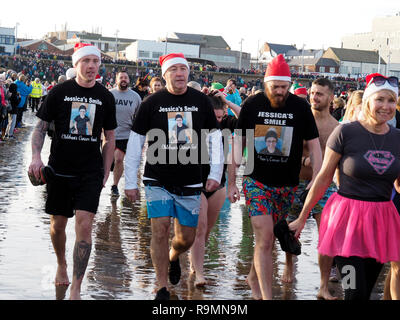 Redcar Cleveland England 26. Dezember 2018. Die jährlichen Boxing Day Liebe 'ip' wurde heute in ungewöhnlich mildes Wetter mit Massen von Menschen an und mit der Rnli und Küstenwache schauen für Sicherheit am Strand in Redcar während, wenn Leute in Fancy Dress gehen in die Nordsee für Spaß und Geld für ihre Nächstenliebe zu heben. Hier drei Männer unterstützen, Jessicas Smile Kinder Krebs Fonds Credit: Peter Jordan NE/Alamy leben Nachrichten Stockfoto