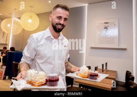 Berlin, Deutschland. 19 Dez, 2018. Benjamin Köhler, Inhaber der Eisdiele La Luna, Waffeln serviert mit Vanilleeis und heißen Kirschen zweimal in seiner Ostseite Mall Eisdiele, mit einem seiner Eintracht Frankfurt Trikots an der Wand hängen. (Dpa 'Zwei Welten': Das neue Leben von Benjamin Köhler" vom 27.12.2018) Quelle: Christoph Soeder/dpa/Alamy leben Nachrichten Stockfoto