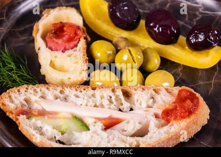 Nahaufnahme einer Sandwich. Sandwich mit Treffen, Prosciutto, Salami, Salat, Gemüse, Salat, Tomaten, Zwiebeln und Senf auf einer frischen in Scheiben geschnittenen Roggen Brea Stockfoto