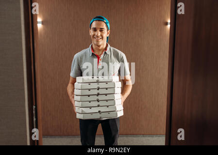 Pizza Delivery Man mit Boxen, Bereitstellung von Service. Kurier aus Pizzeria hält Pappe im Innenbereich Stockfoto