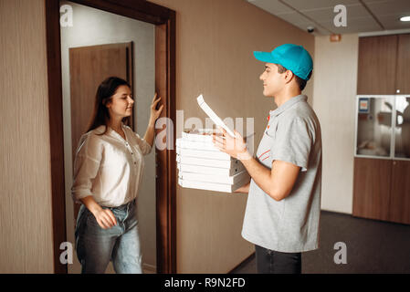 Weibliche Kunden und Lieferung Junge prüft, Pizza, schnellen Service. Kurier aus Pizzeria und die Frau an der Tür Stockfoto