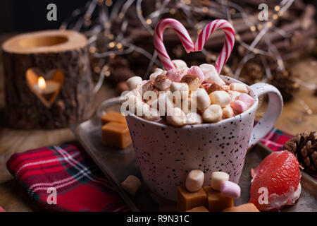 Kakao mit Marshmallows in eine weiße Tasse, verschiedene Weihnachten Bonbons und Süßigkeiten. Foto in dunklen Stil und freier Platz für Text. Kerzen und Urlaub Dekor Stockfoto