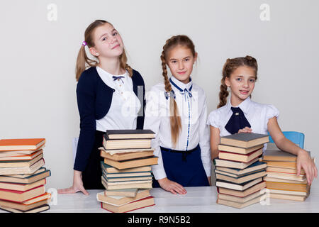 Drei Mädchen Schülerinnen an einem Schreibtisch mit Büchern über die Lektion in der Schule Stockfoto