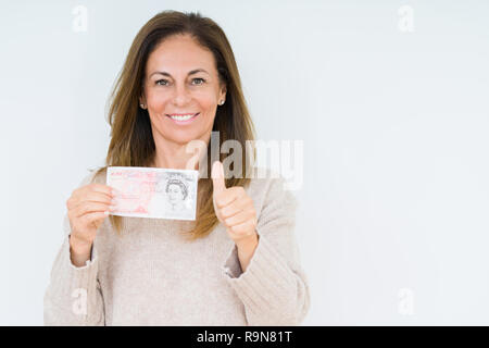 Mittleres Alter Frau mit 50 Pfund Bank Note über isolierte Hintergrund mit Lächeln tun ok Zeichen glücklich, Daumen hoch, mit den Fingern, ausgezeichnete Zeichen Stockfoto