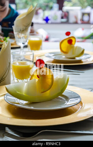 Ein Stück Melone wie eine Melone Boot auf einer Platte auf ein Esszimmer Tisch bereit Als ersten Gang zu essen präsentiert. Stockfoto