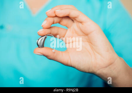 Nahaufnahme einer Ärzte hand mit modernen Hörgerät Hörgeräte - Taubheit Behandlung Stockfoto
