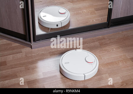 Roboter Staubsauger auf Laminatboden im Spiegel der Schrank reflektiert wird, smart home Robotics Wireless Reinigung für Vereinfachen Sie routinemäßige Hausarbeit, effic Stockfoto