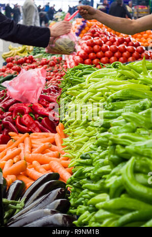 Frisches und organisches Gemüse auf dem Bauernmarkt. Hand und Hand des Käufers auf verschwommenem Hintergrund. Stockfoto