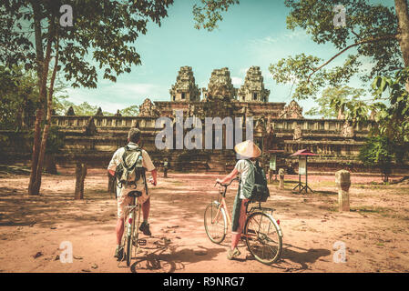 Touristische paar Radfahren rund um Tempel Angkor, Kambodscha. Ta Keo Gebäude Ruinen im Dschungel. Umweltfreundliche Tourismus Reisen, getönten Bild. Stockfoto