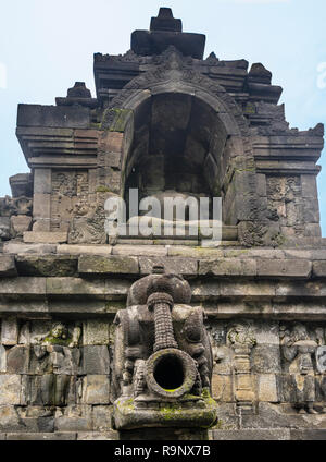 Geschnitzte Regenwasser Auslauf unten eine kopflose sitzende Buddha Statue in einer Nische im 9. Jahrhundert Borobudur Mahayana-buddhistischen Tempel, Central Java, Indonesien Stockfoto