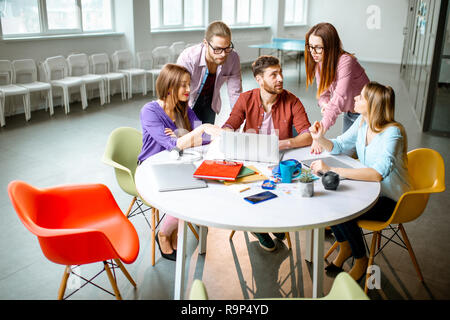 Gruppe von einem jungen Mitarbeiter lässig gekleidet gemeinsam mit Laptops im modernen Büro Stockfoto