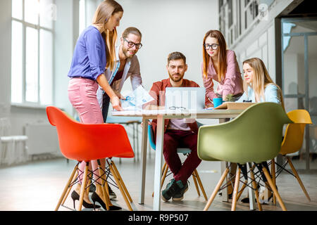Gruppe von einem jungen Mitarbeiter lässig gekleidet gemeinsam mit Laptops im modernen Büro Stockfoto