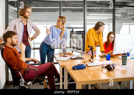 Gruppe von jungen, kreativen Mitarbeitern Entwerfen eines Pkw-Modell am Arbeitsplatz mit Computern im modernen Büro innen Stockfoto