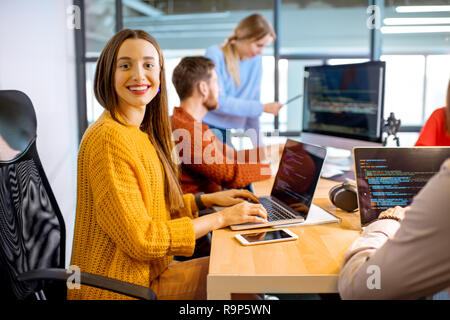 Team einer jungen Frau als Programmierer im Büro mit Menschen, die auf dem Hintergrund Stockfoto