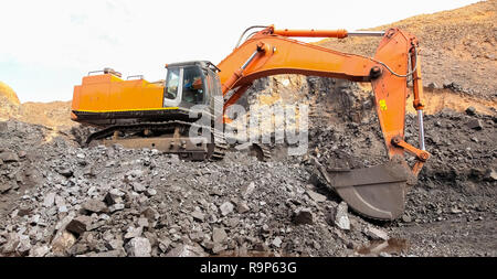 Bagger graben und Laden von Erz Felsen auf ein Mangan mine Stockfoto