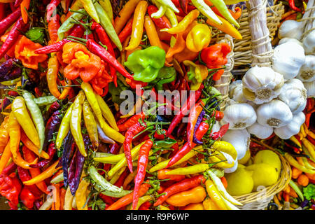 Bunte Vielfalt an frischen Chili und Knoblauchzwiebeln auf einem Gemüsemarkt in Valencia, Spanien Stockfoto