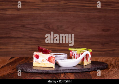 Stück Kuchen auf schwarze Platte mit Erdbeeren. Holz- Hintergrund Stockfoto