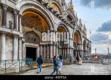 Touristen pass Saint Mark's Basilika Kathedrale Saint Mark's Square mit den Säulen von San Marco und San Todaro Angesichts in Venedig, Italien Stockfoto