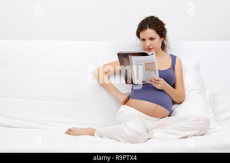 Junge schwangere Frau eine Zeitschrift liest Stockfoto