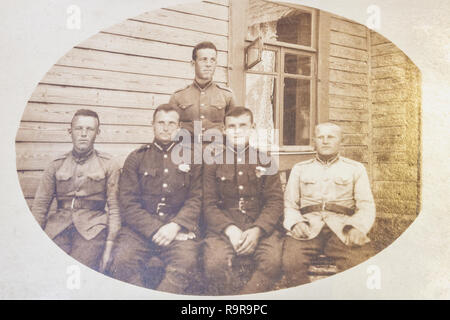 Lettland - 1930er Jahre: Eine antike Foto zeigt fünf Soldaten vor Holzhaus posing Stockfoto