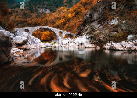 Devil's Bridge, Bulgarien. Alte steinerne Brücke über Fluss Arda, Herbst Zeit mit Blätter in Wasser. Rhodope Berg Stockfoto