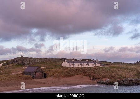 Der Pilot Cottages und Kreuz auf Ynys Llanddwyn auf Anglesey, Nordwales bei Sonnenaufgang. Stockfoto