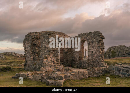 Die Ruine der Kirche und der Sächsischen Kreuz auf Ynys Llanddwyn auf Anglesey, Nordwales bei Sonnenaufgang. Stockfoto