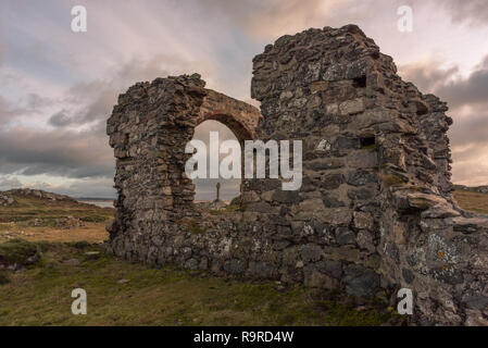 Die Ruine der Kirche und der Sächsischen Kreuz auf Ynys Llanddwyn auf Anglesey, Nordwales bei Sonnenaufgang. Stockfoto