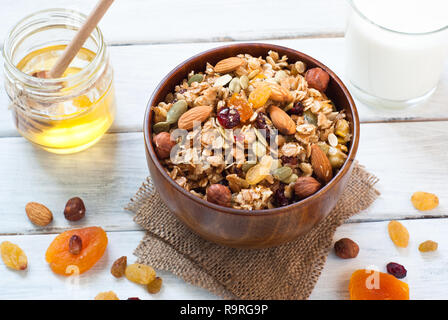 Müsli Müsli flakes mit getrockneten Früchten, Nüssen und Honig in eine Schüssel geben. Stockfoto