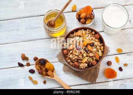 Müsli Müsli flakes mit getrockneten Früchten, Nüssen und Honig in eine Schüssel geben. Stockfoto