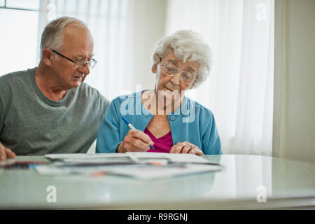 In dem Bestreben, ältere Paare anmelden Papierkram, während Sie durch Ihre große Stapel von Rechnungen. Stockfoto