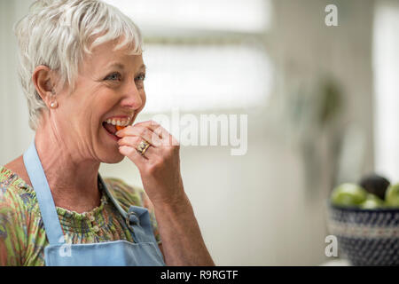 Lächelnd reife Frau werfen einer frisch zubereiteten Salat. Stockfoto