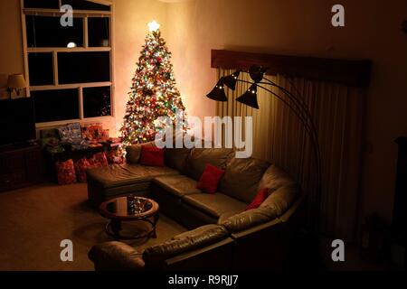 Eine warme Weihnachten Szene in weiches Licht im Familienzimmer mit einem großen Weihnachtsbaum und einige eingepackte Geschenke. Stockfoto