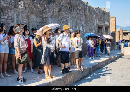 Japanische Touristen, Mützen Regenschirm Regenschirme Vordächer, Sonnenschutz Sun, Pompeji, Italien, touristische Konzept, Travel besuchen Sie erkunden erkunden heißen Tag Sonnenschirm sun Stockfoto