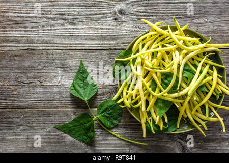Frische Bohnen, gelbe organische Bohnen auf Platte auf hölzernen Tisch Stockfoto