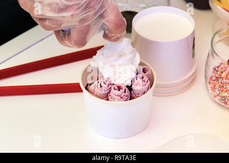 Stir-gebratenes Eis rollt mit freeze Pan. Gerollt Ice Cream, handgearbeitet Eis Dessert. Wokgemüse Eis aus Milch und Berry jam. Gebratene Maschine w Stockfoto